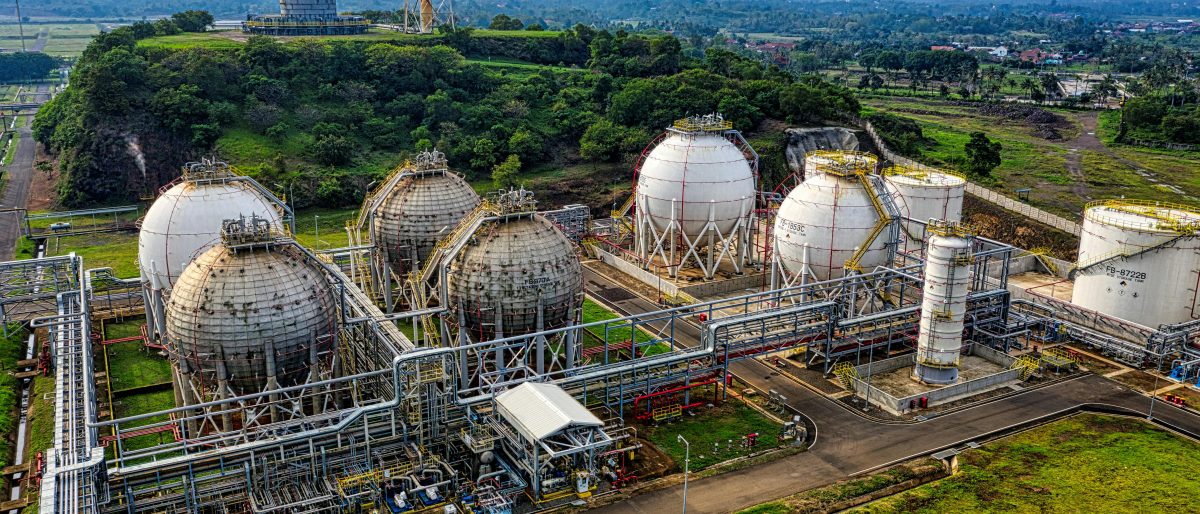 Aerial shot of a power plant with storage tanks in lush Banten, Indonesia offers an impressive scale.