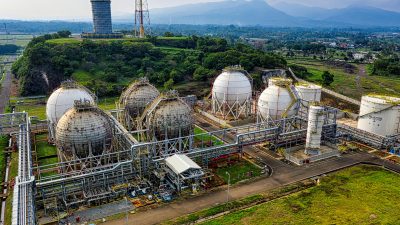 Aerial shot of a power plant with storage tanks in lush Banten, Indonesia offers an impressive scale.